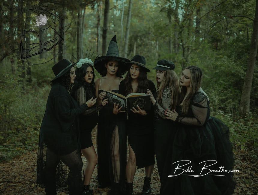 Group of women dressed as witch coven reading spell book in forest