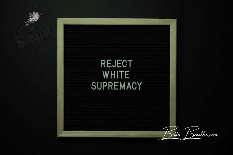 Top view of blackboard with written white REJECT WHITE SUPREMACY words on center on black background