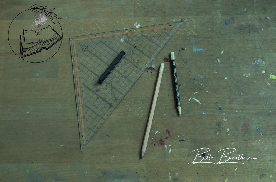 Measuring triangle ruler and pencils on table