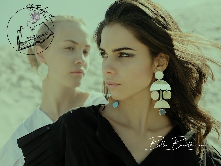 Attractive brunette woman with elegant hairdo wearing black dress with fashionable earrings and makeup standing in front of young blond female friend with simple hairstyle and without makeup in white shirt