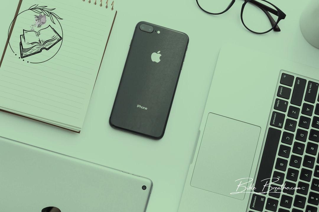 space gray iPhone X beside MacBook