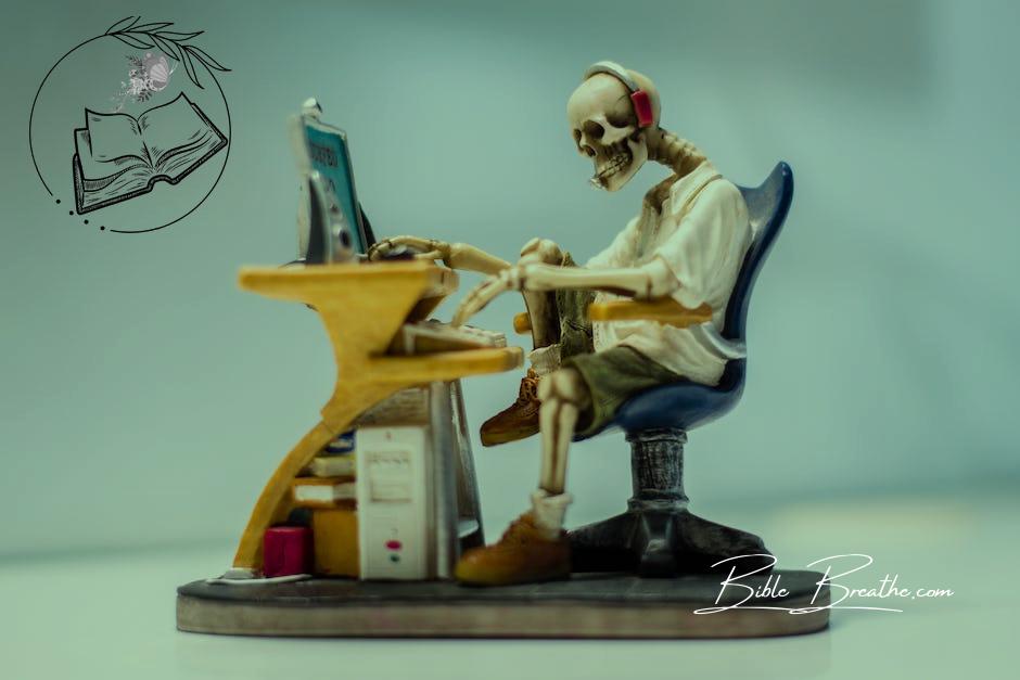 Figurine of Human Skeleton Sitting Infront of Computer