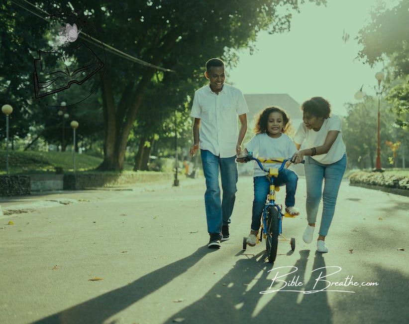 Man Standing Beside His Wife Teaching Their Child How to Ride Bicycle