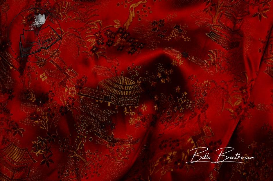 Background of bright fabric with authentic oriental ornaments of floral patterns and traditional huts on creased surface of red textile