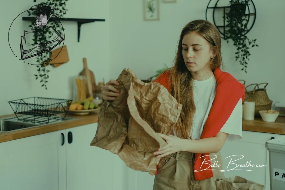 Young serious female with long hair sorting reusable paper trash in modern kitchen in apartment