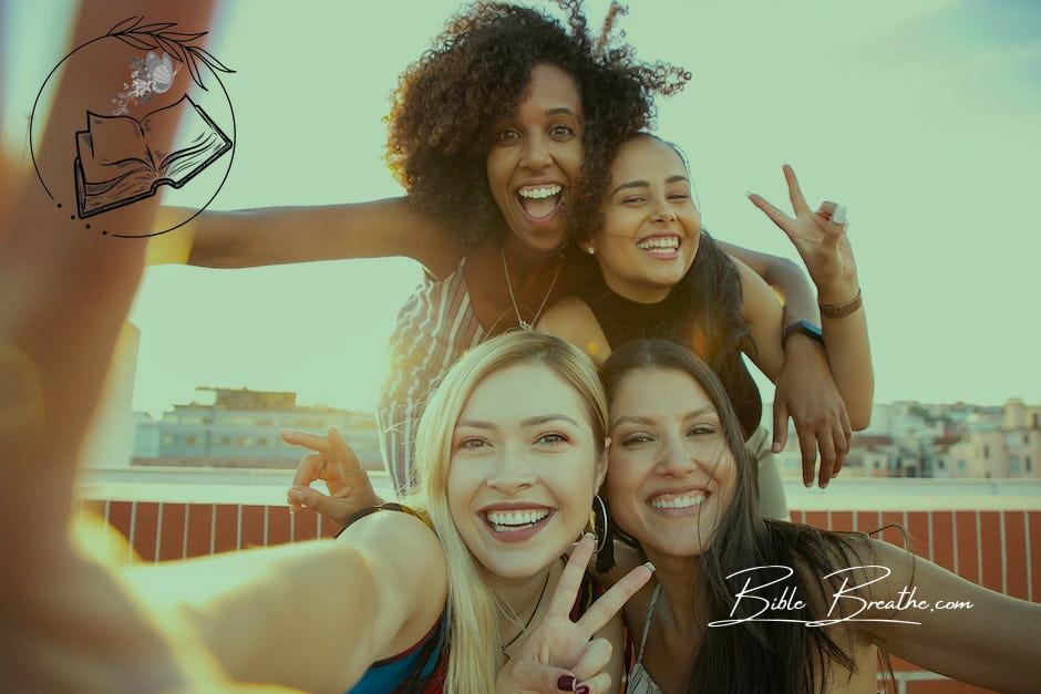 Cheerful young diverse women showing V sign while taking selfie on rooftop