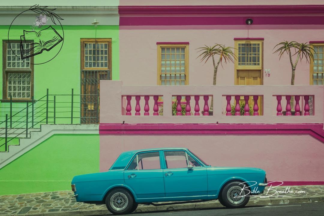 blue coupe in front of pink house