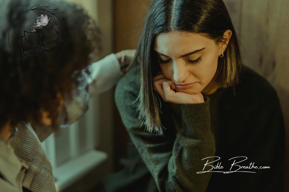 Crop woman tapping shoulder and comforting upset female friend while sitting at home together