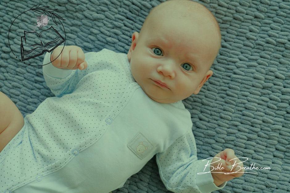 Baby in White Onesie Lying on Grey Textile