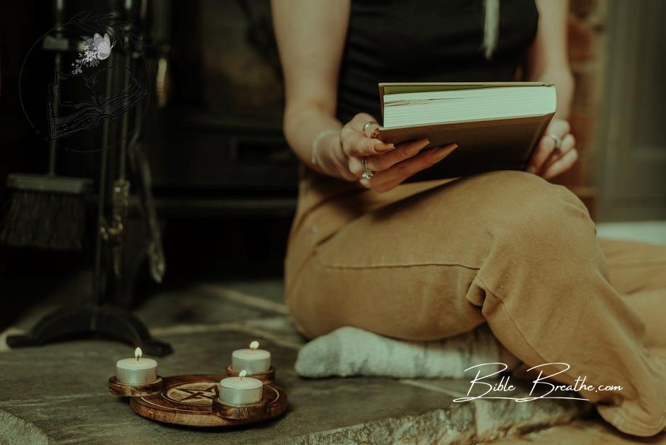 Witch opening book near pentagram sign and sparkling candles