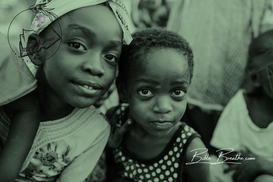 Black and white glad children in casual clothes standing on authentic town street and looking at camera with curiosity