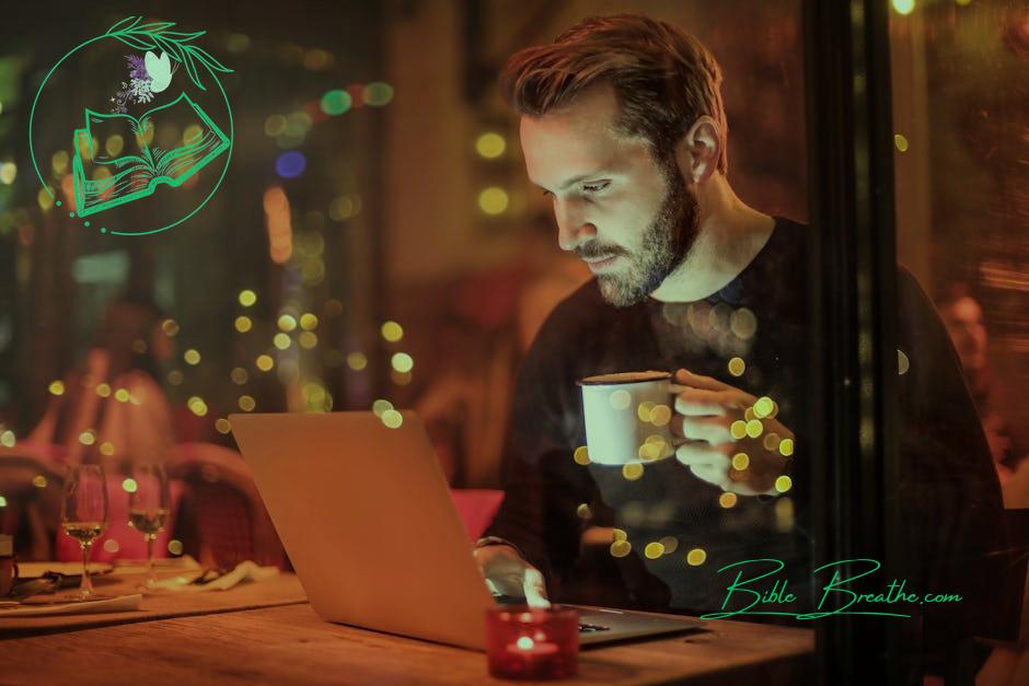 Man Holding Mug in Front of Laptop