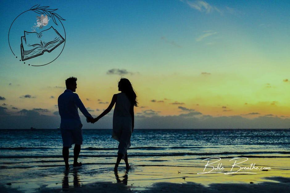 Man and Woman Holding Hands Walking on Seashore during Sunrise