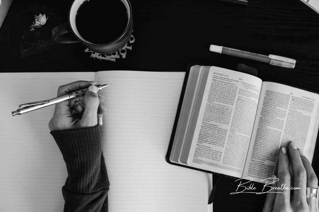 Woman's hands with Bible open and blank notebook