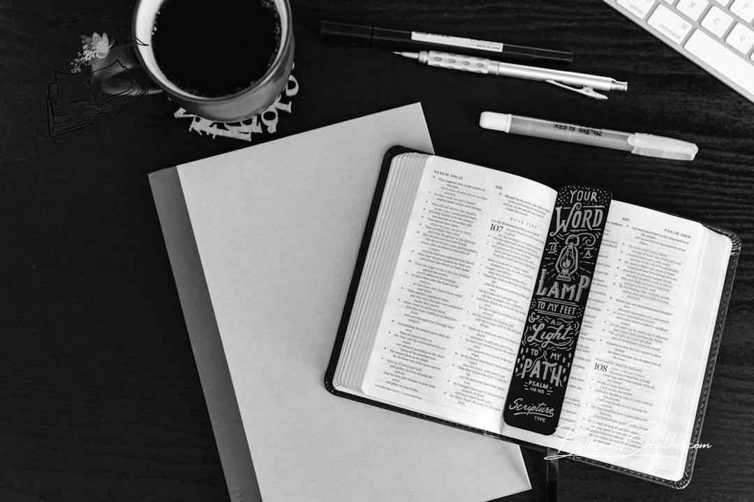 Bible open with bookmark, coffee, and writing tools